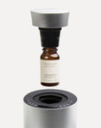 Lavender EssenAn instructional close-up showing a 10ml lavender essential oil bottle screwing into a black nozzle mechanism above a silver waterless diffuser.tial Oil - 10ml - VAUCLUSE