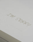Close-up macro view showing the textured white cardstock and fine debossed details of the elegant "I'm Sorry" apology message.