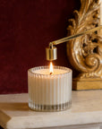 A classic gold bell candle snuffer being used to safely extinguish a burning candle flame on a mantlepiece.