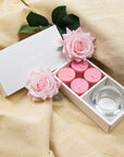 Elegant aromatherapy lifestyle scene featuring the open rose tealight gift box styled on draped beige linen fabric with light pink decorative roses.