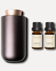 A metallic bronze waterless nebulizing aroma diffuser displayed next to two 10ml amber bottles of vaucluse tuberose essential oil.