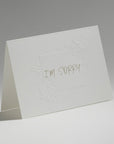 An elegant, freestanding white apology greeting card featuring the text "I'm Sorry" centered within a delicate embossed floral border.