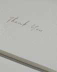 Side angle close-up emphasizing the crisp cursive typography and premium embossed floral details on a luxury corporate thank you note.