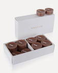 An open premium white gift box filled with brown Vaucluse Cinnamon scented tealight candles.
