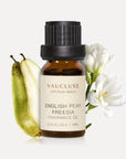 A 10ml amber glass bottle of Vaucluse English Pear and Freesia Essential Oil, flanked by a sliced green pear and elegant white freesia flowers.