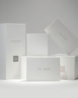 A curated stack of premium white Vaucluse fragrance gift packaging boxes and candle boxes arranged alongside the minimalist "I'm Sorry" greeting card.