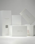 A curated collection of premium minimalist white Vaucluse fragrance boxes, candle packaging, and the elegant thank you card neatly arranged on a white surface.