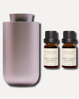 Two 10ml Vaucluse Honey Jasmine and Cypress essential oil amber bottles positioned next to a sleek metallic aroma diffuser.