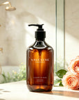 Vaucluse Lumière de Rose body wash placed on a bathroom counter next to fresh pink roses.