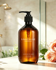 Vaucluse Lumière de Rose body wash placed on a bathroom counter next to fresh pink roses.