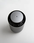 An overhead top-down view of the circular black and silver waterless diffuser highlighting its central mist nozzle and touch-sensitive interface.