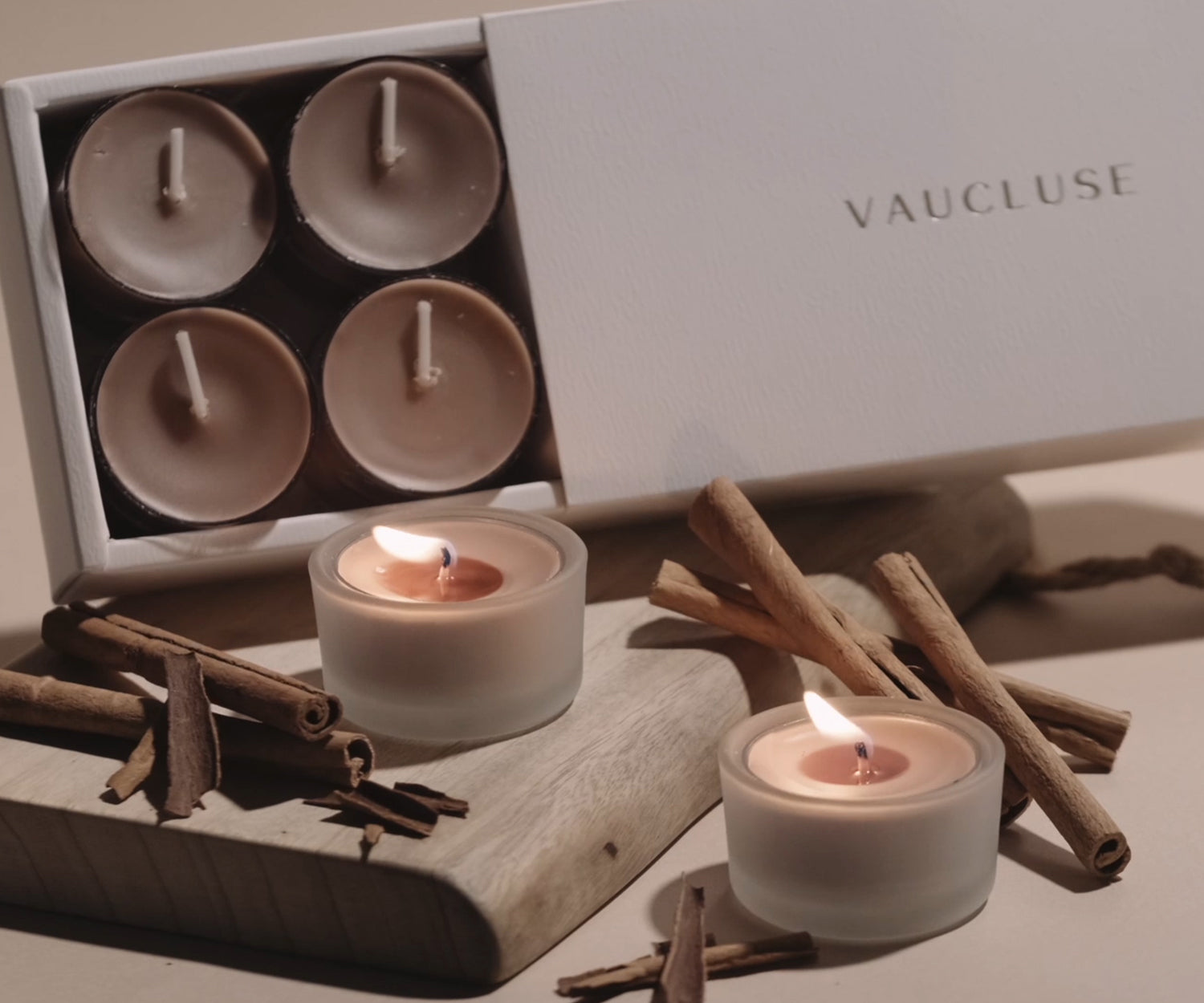 Vaucluse premium warm cinnamon soy tealight candles burning on a rustic wooden table.