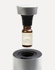 An explanatory graphic of a 10ml Vaucluse amber oil bottle screwing upward into a black adapter collar for a silver nebulizing diffuser.