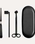 Matte black candle care accessory set featuring a wick trimmer, candle snuffer, wick dipper, and matching oval tray on a clean white background.