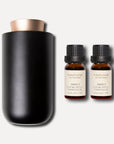 A minimalist black waterless aroma diffuser displayed alongside two 10ml bottles of Vaucluse Amber Eucalyptus Essential Oil.