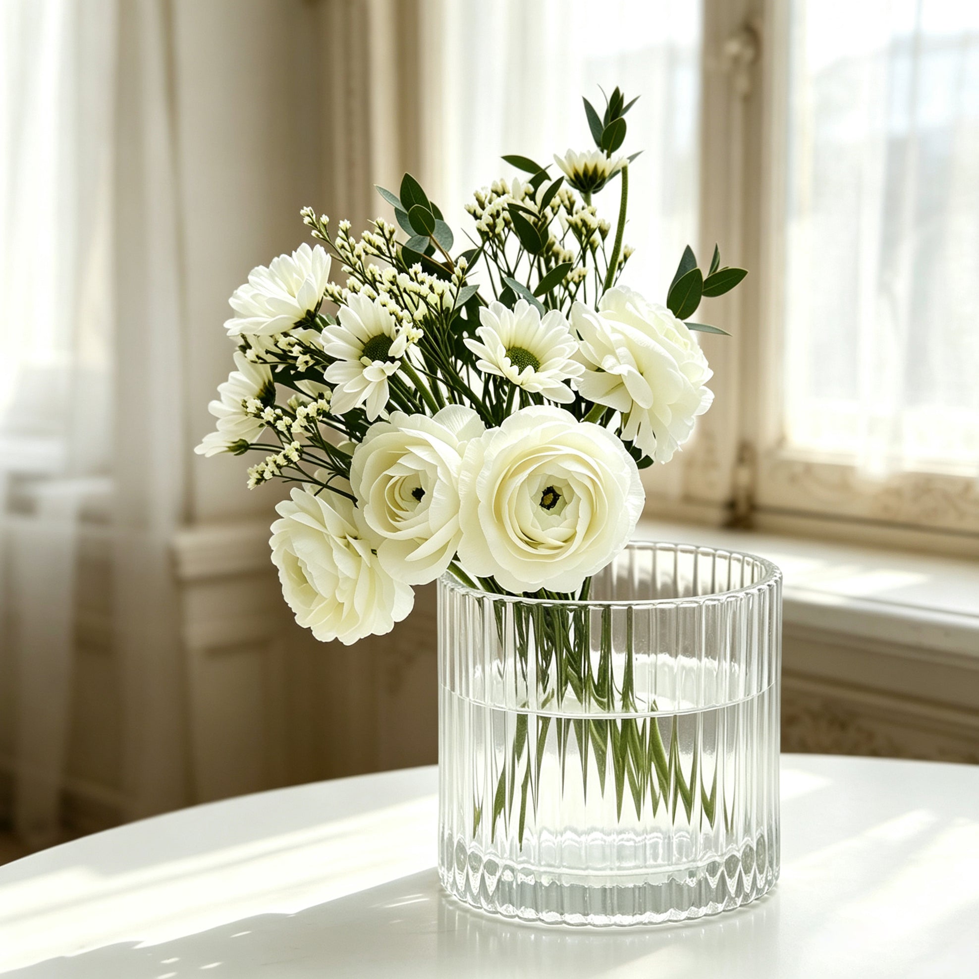 A luxury ribbed glass candle tumbler transitioned into an elegant, minimal flower vase filled with fresh white ranunculus flowers on a table.