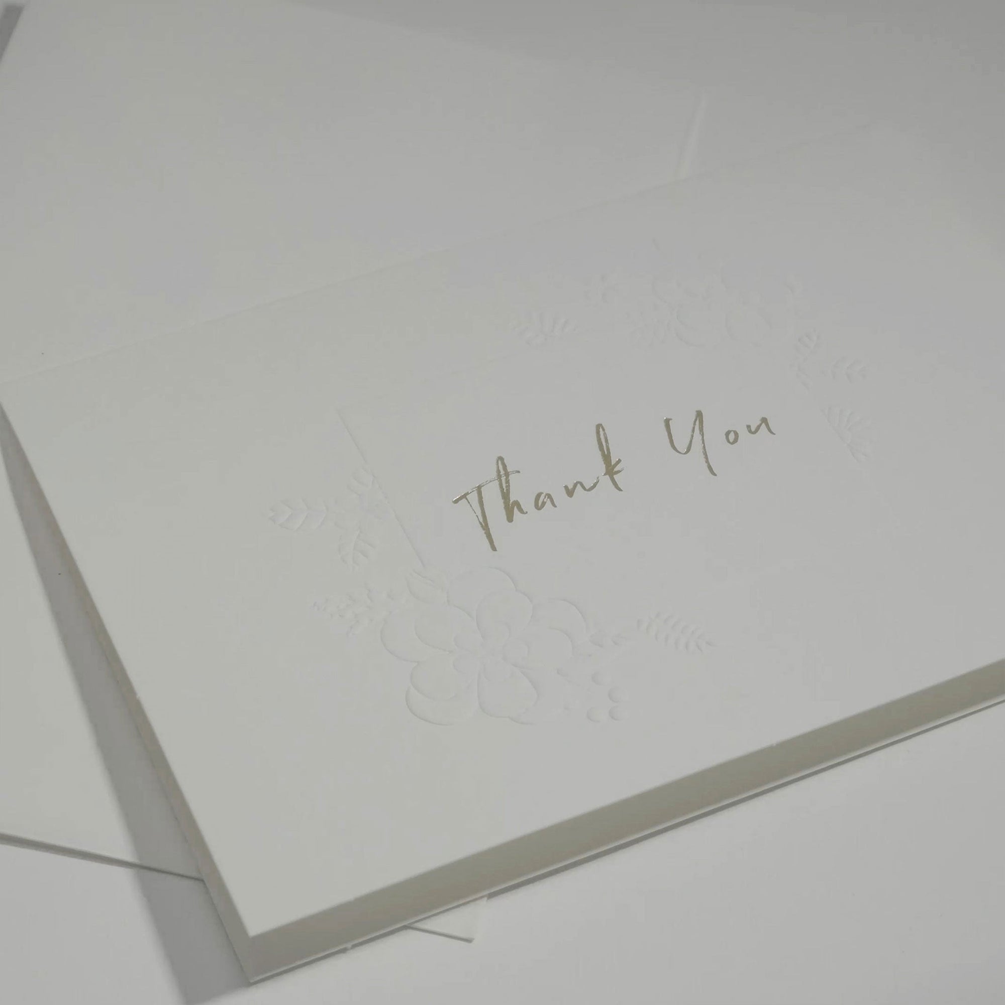 Side angle close-up emphasizing the crisp cursive typography and premium embossed floral details on a luxury corporate thank you note.