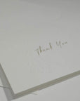 Side angle close-up emphasizing the crisp cursive typography and premium embossed floral details on a luxury corporate thank you note.