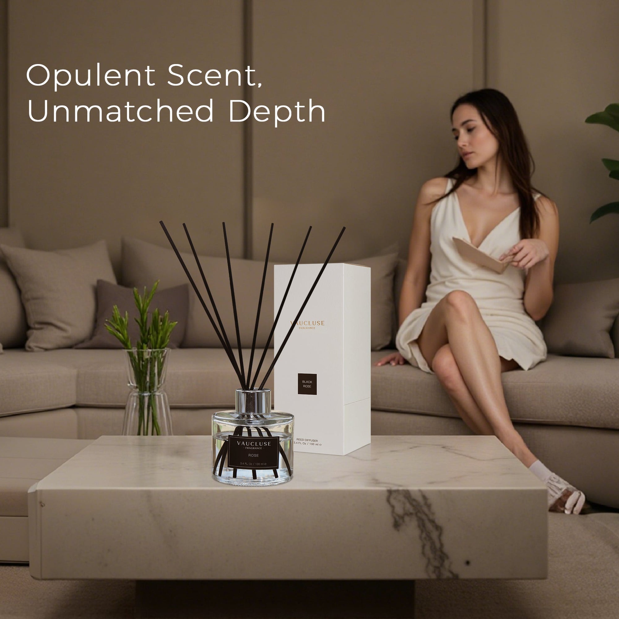 An opulent Vaucluse black rose reed diffuser showcased on a modern marble coffee table, with a woman in an elegant dress sitting on a beige couch in the background.