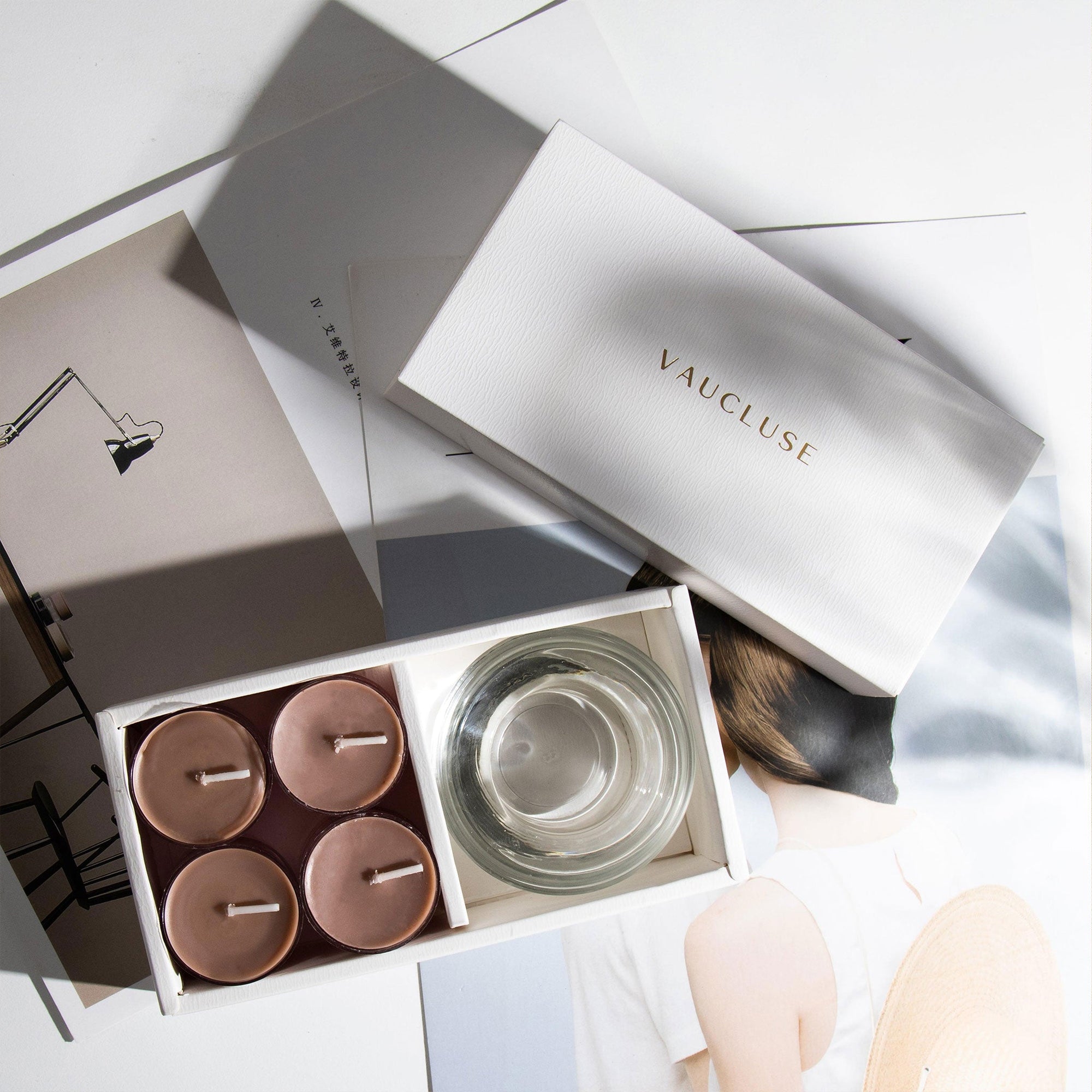 Overhead aesthetic view of the luxury scented cinnamon tealight candle gift set sitting on top of minimalist editorial design books and magazines.