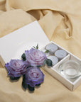 Elegant lifestyle scene featuring the open velvet tealight gift set styled on draped beige linen fabric with decorative purple roses.