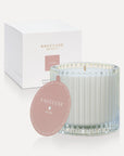 Vaucluse Lychee luxury scented soy wax candle in a clear ribbed glass tumbler jar displayed next to its rose pink dust cover lid and minimalist white gift box.