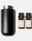 A sleek matte black waterless nebulizing diffuser placed next to two 10ml bottles of gardenia essential oil.