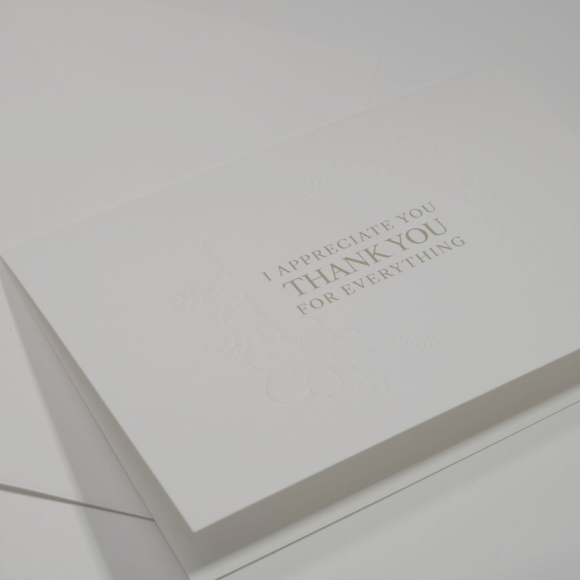 Side angle close-up emphasizing the crisp, clean typography and elegant floral embossing framework on a luxury white appreciation card.