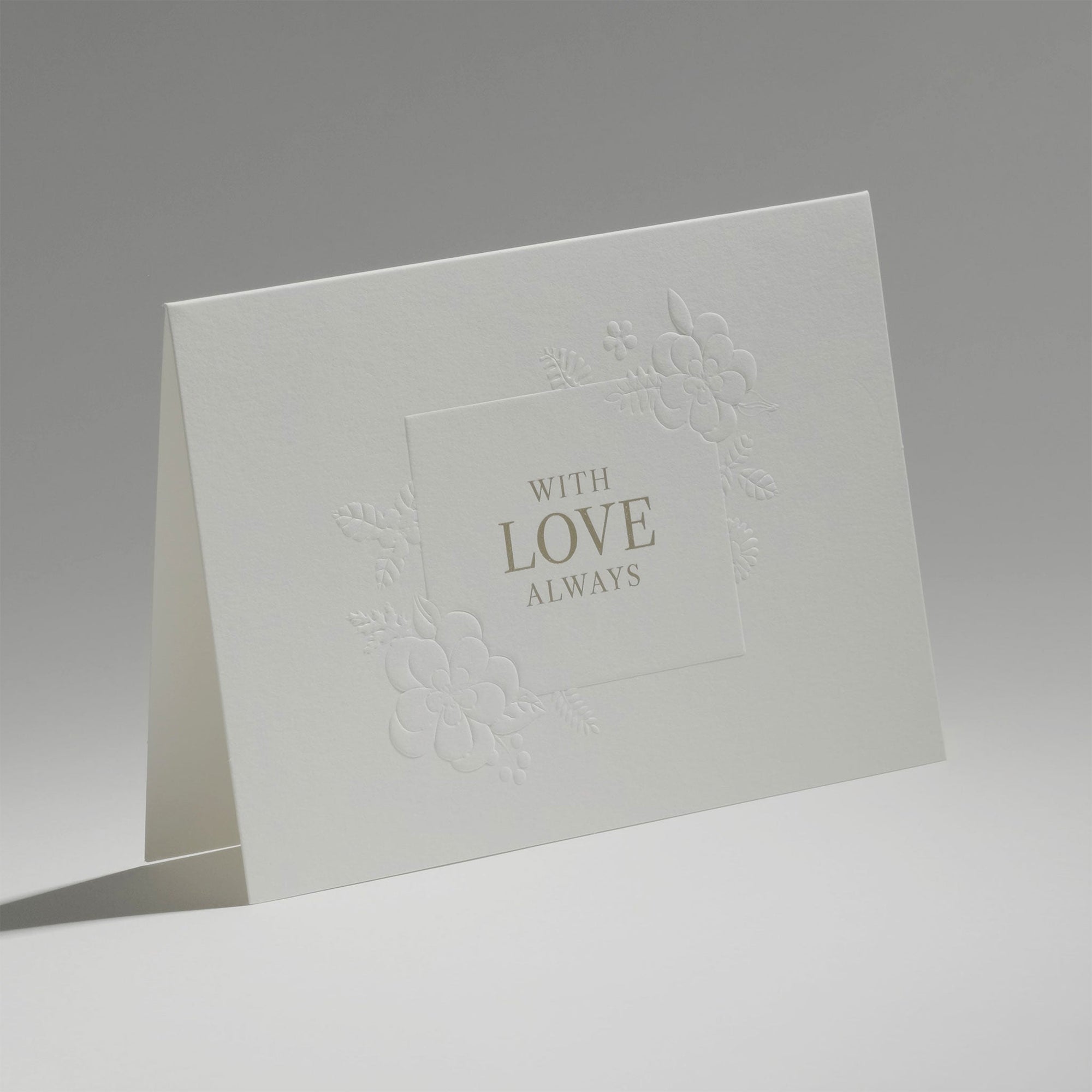 An elegant, freestanding white love card showcasing a delicate debossed floral motif framing the central typography.