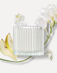 Vaucluse ribbed glass candle jar surrounded by fresh sliced pears and white freesia flowers against a clean background, representing the product's fragrance notes.