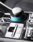 A portable teal and silver electronic diffuser resting securely inside a luxury car cup holder console for mobile aromatherapy.