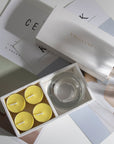 Aesthetic top-down view of the premium lemon scented tealight candle gift box arranged over modern minimalist design books.