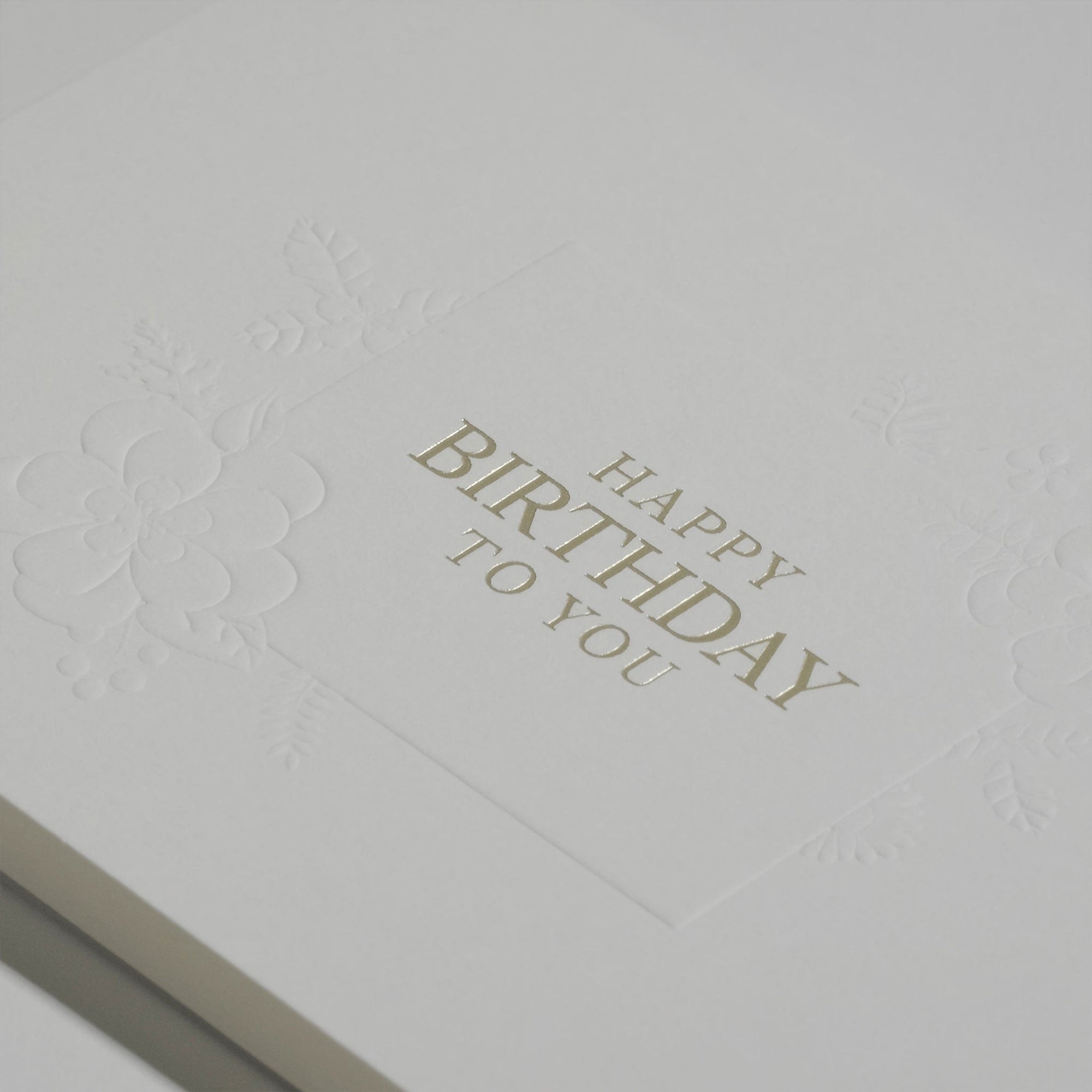 Close-up macro view highlighting the rich, heavy paper texture and crisp gold foil embossing on the Vaucluse "Happy Birthday To You" message.