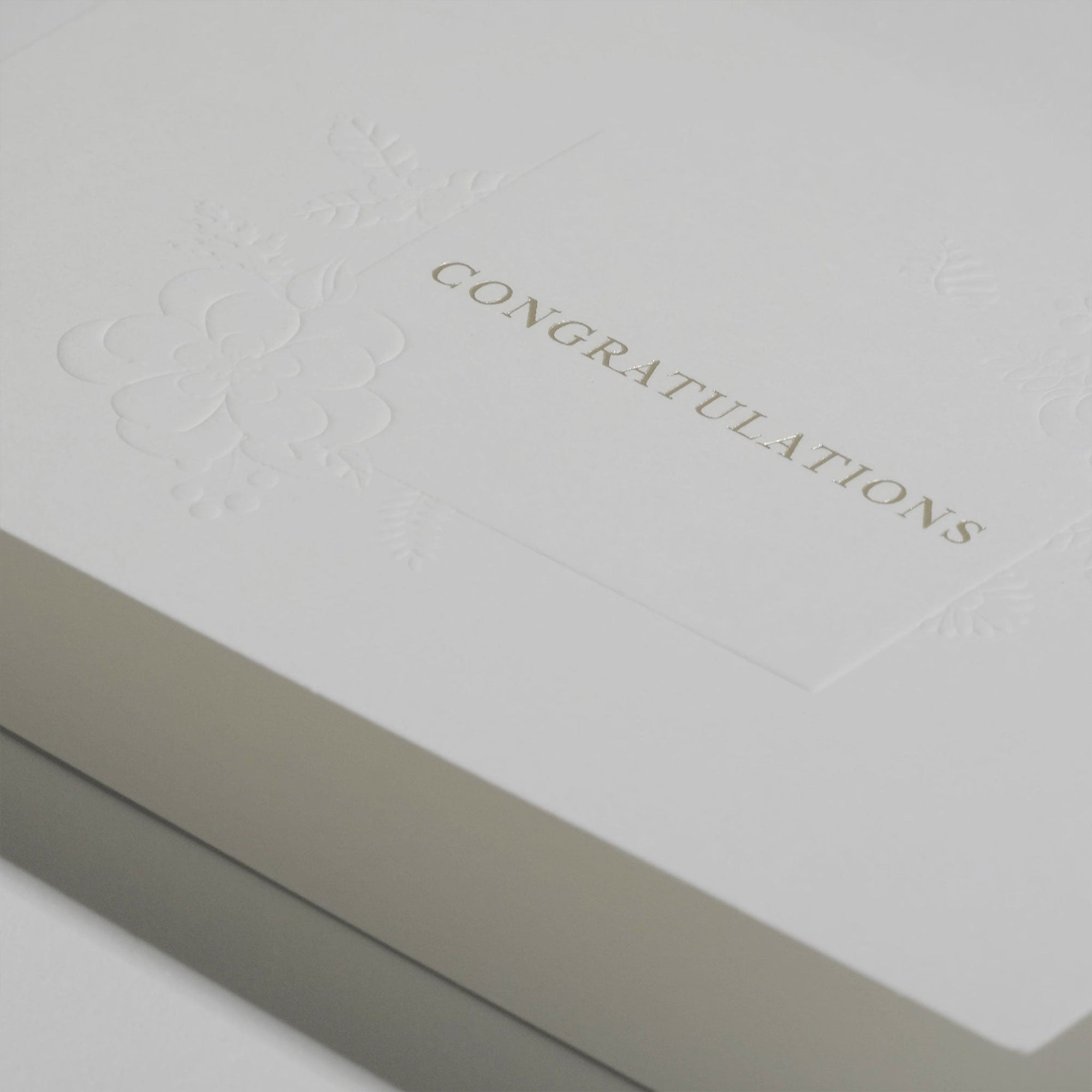 Close-up macro view highlighting the rich textured paper and fine gold metallic embossing on the Vaucluse luxury congratulations card.