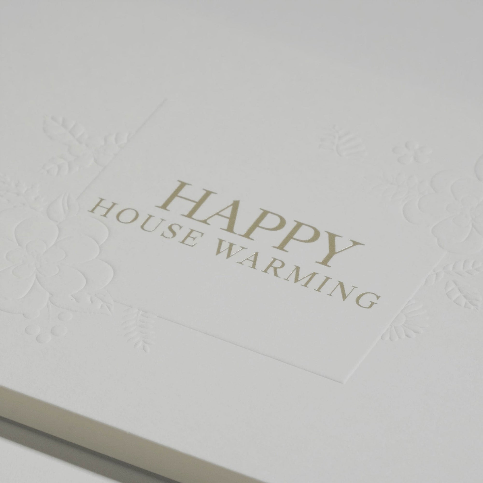 Close-up macro shot highlighting the heavy textured cotton paper and fine gold metallic lettering on the Vaucluse luxury housewarming card.