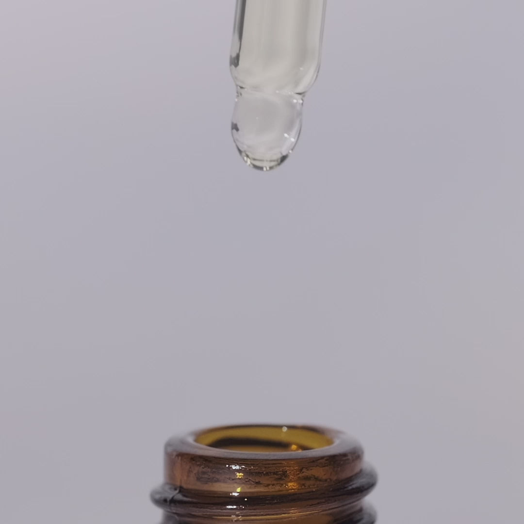 A close-up video thumbnail showing a single clear drop of Vaucluse essential oil suspended from a glass pipette directly over the rim of an open amber bottle.