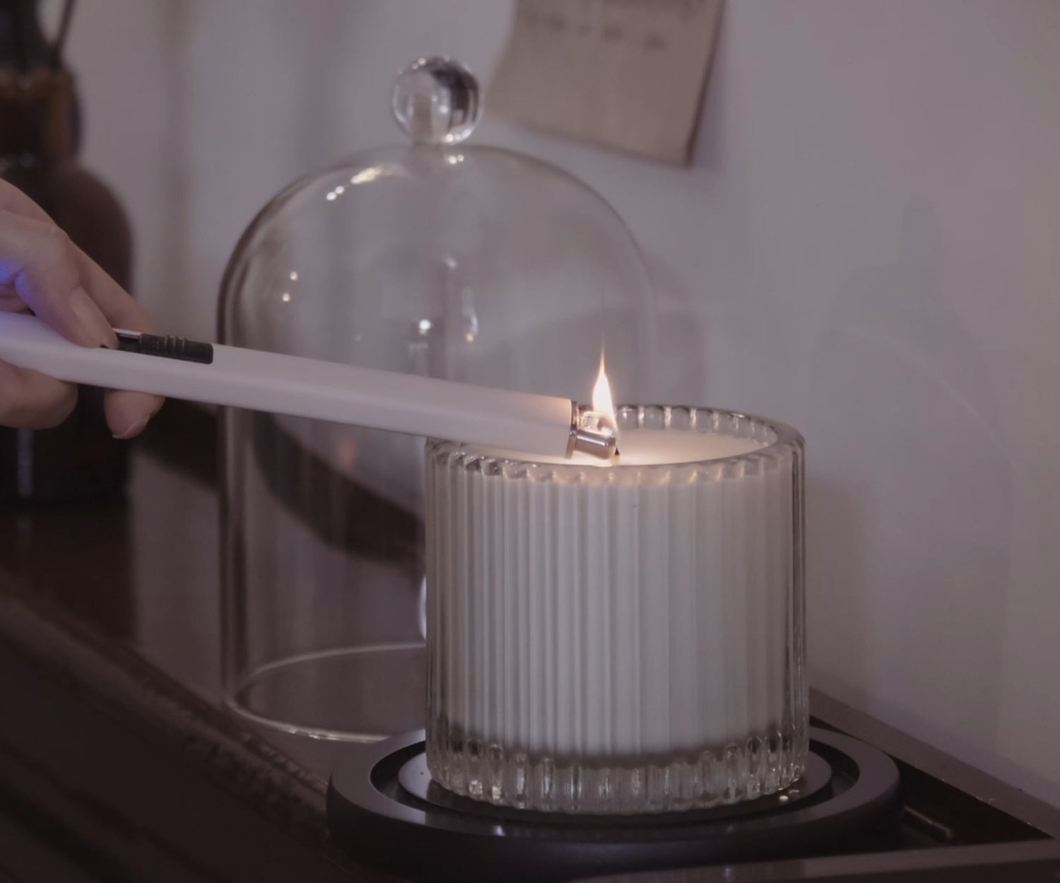 Lighting a luxury scented glass candle with a white rechargeable electric lighter