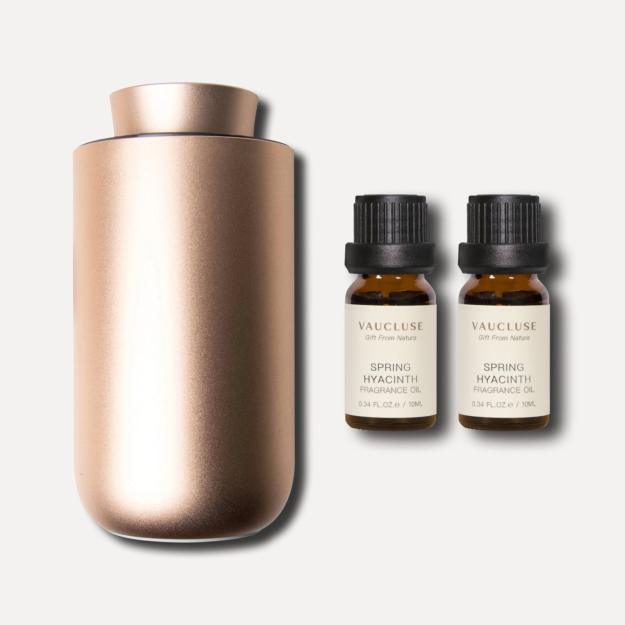 A metallic rose gold waterless nebulizing aroma diffuser displayed beside two 10ml Vaucluse amber bottles of spring hyacinth essential oil.