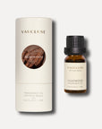 A 10ml bottle of agarwood essential oil standing next to its elegant white cylindrical tube packaging featuring a circular wood grain design.