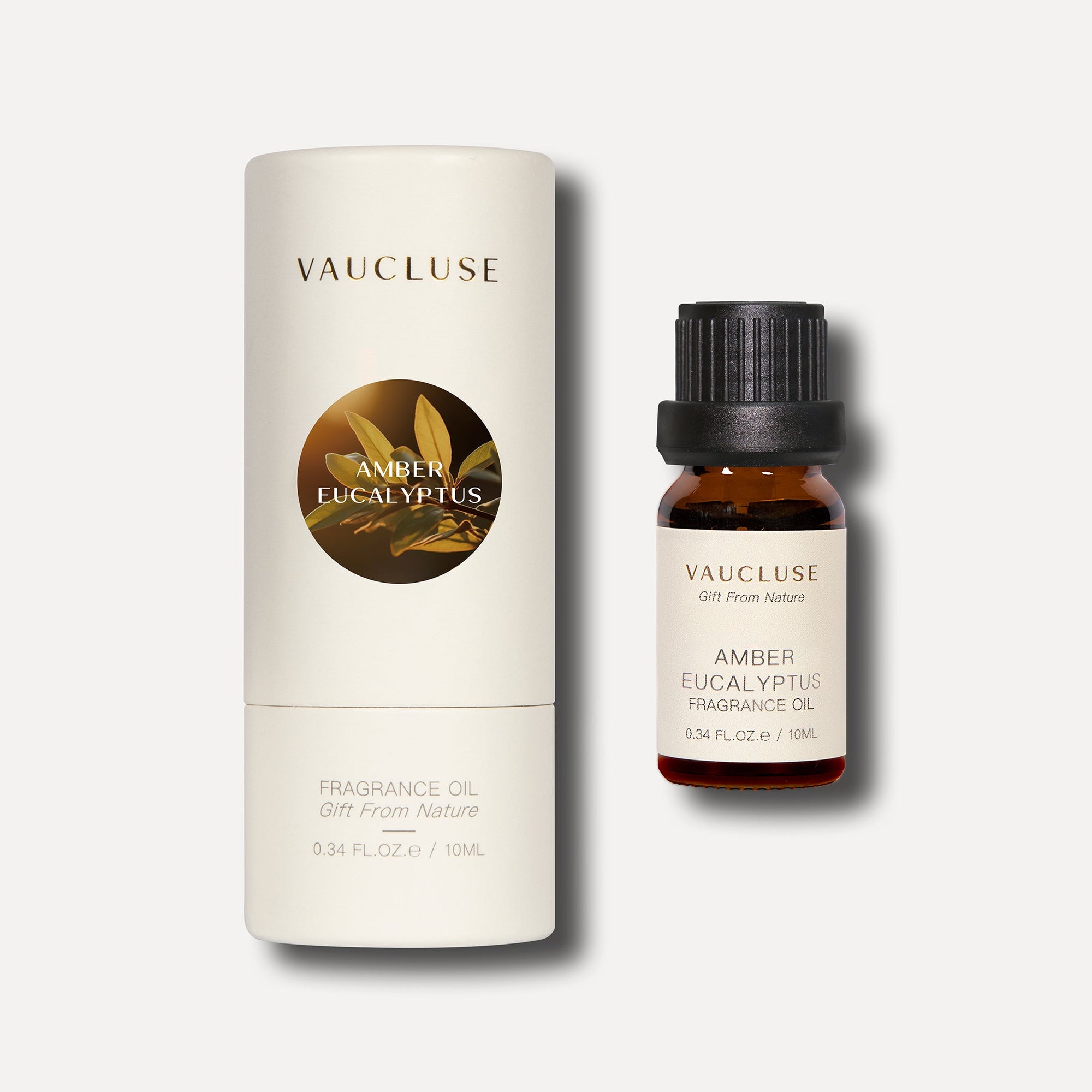A 10ml amber bottle of Vaucluse Amber Eucalyptus Essential Oil next to its cream-colored cylindrical cardboard packaging tube featuring a round metallic icon.