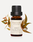 A 10ml amber glass bottle of Vaucluse Amber Eucalyptus Essential Oil flanked by warm-toned, earthy eucalyptus leaves and seed pods.