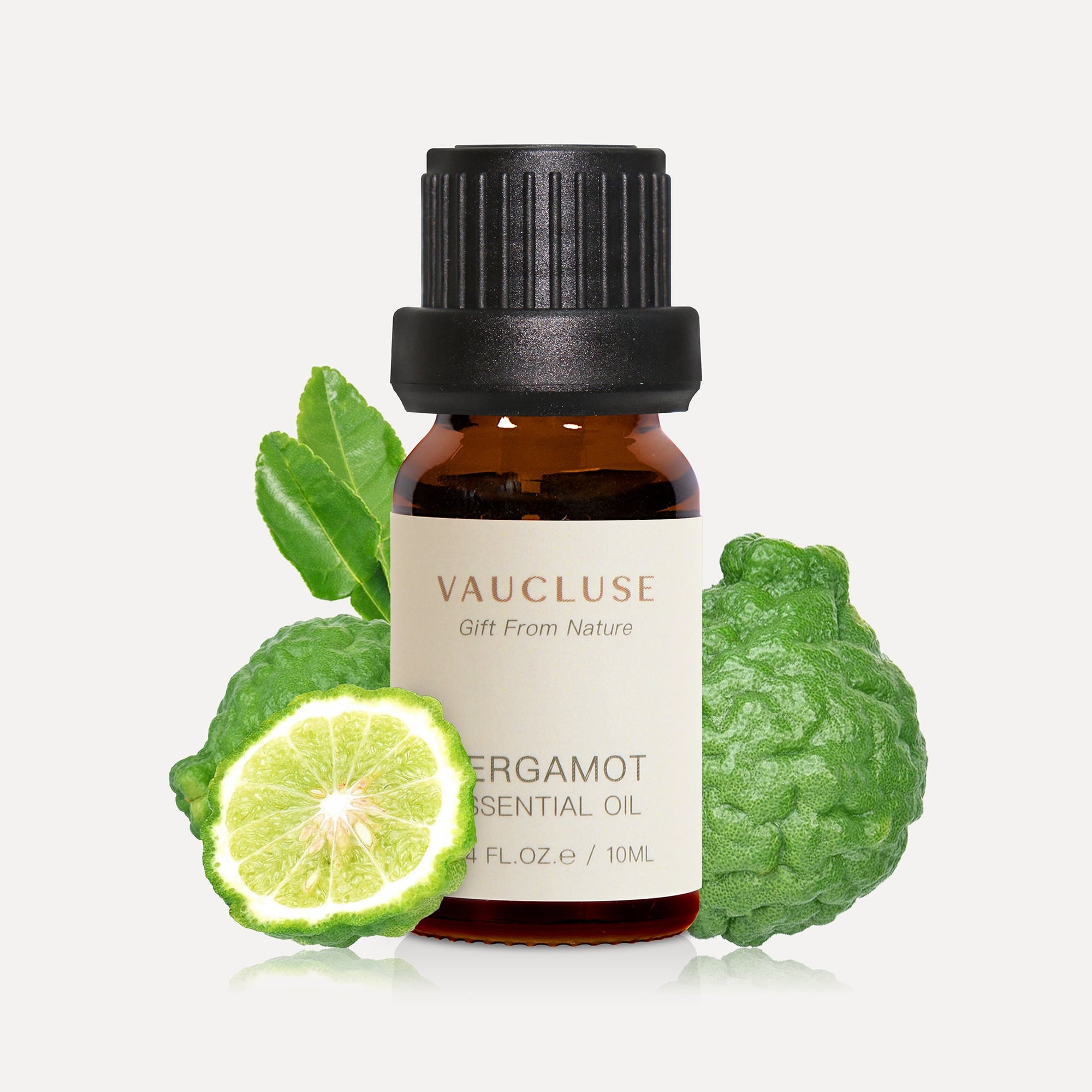 A 10ml amber glass bottle of Vaucluse Bergamot Essential Oil backed by a whole wrinkled green bergamot fruit and a fresh citrus slice.