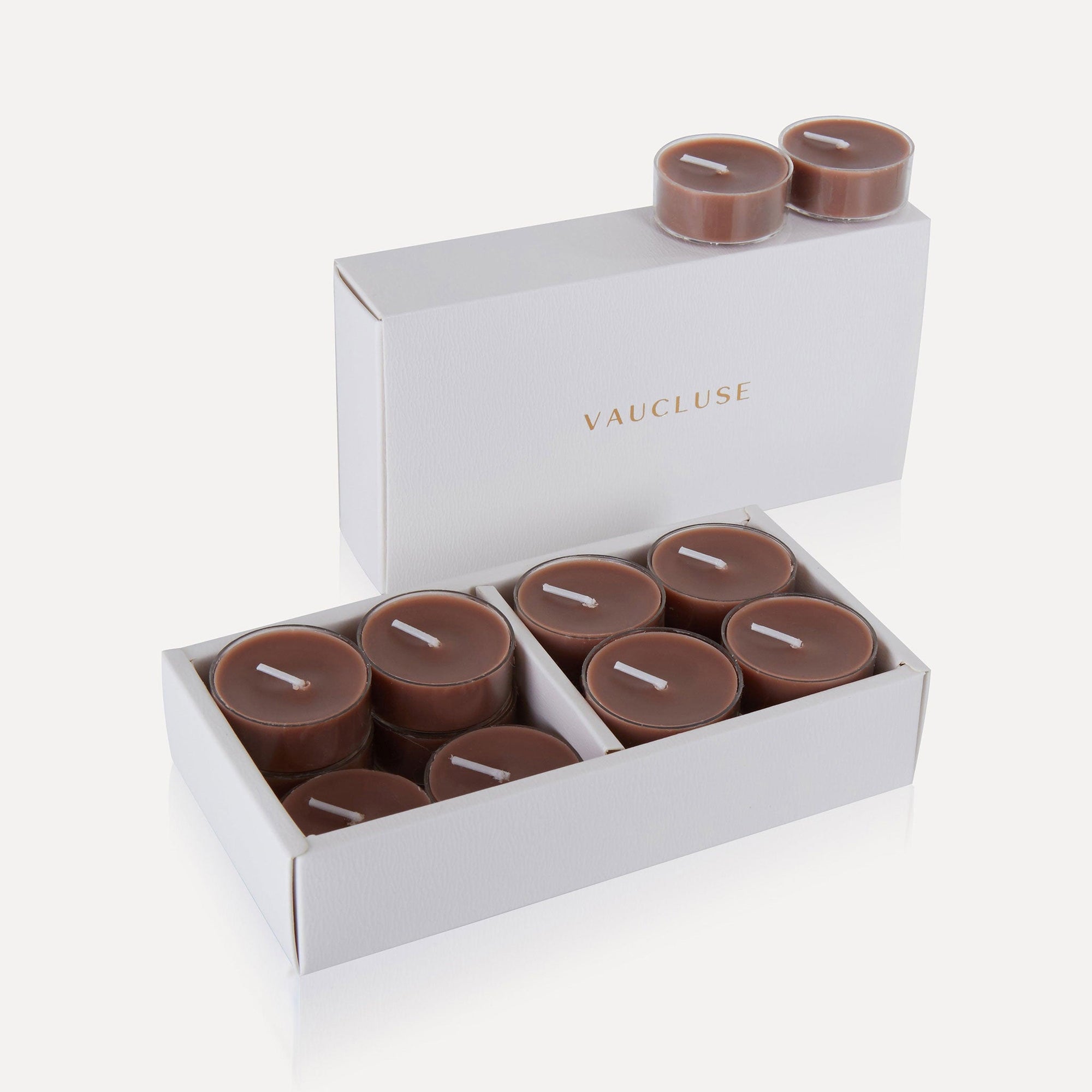 An open premium white gift box filled with brown Vaucluse Cinnamon scented tealight candles.