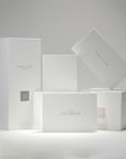 A curated collection of premium minimalist white Vaucluse fragrance boxes, candle packaging, and the elegant Let's Celebrate card arranged neatly on a crisp white surface.