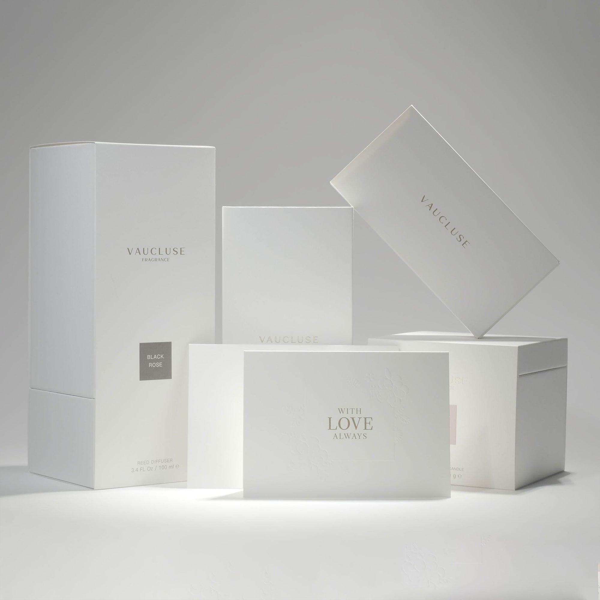 A curated collection of premium minimalist white Vaucluse fragrance boxes, candle packaging, and the elegant With Love Always card neatly arranged on a white surface.