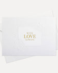 Overhead view of a minimalist luxury white romantic greeting card featuring gold foil text reading With Love Always, displayed with its matching envelope.