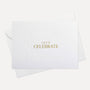 Front flat lay view of a minimalist luxury white celebration card featuring elegant gold text reading Let's Celebrate, displayed with its matching white envelope.