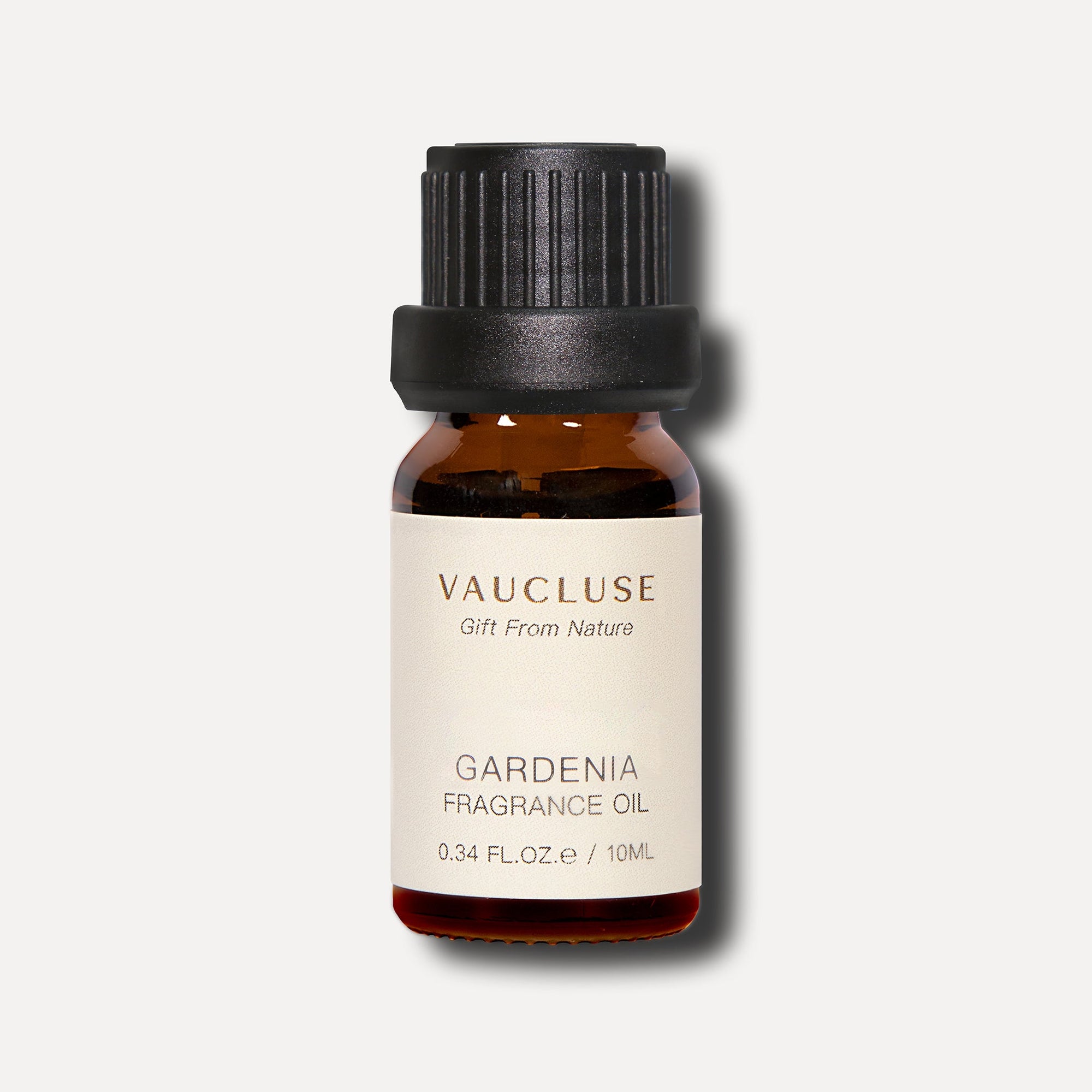 A front studio shot of a 10ml amber glass bottle of Vaucluse Gardenia Essential Oil with a black screw cap casting a soft shadow.