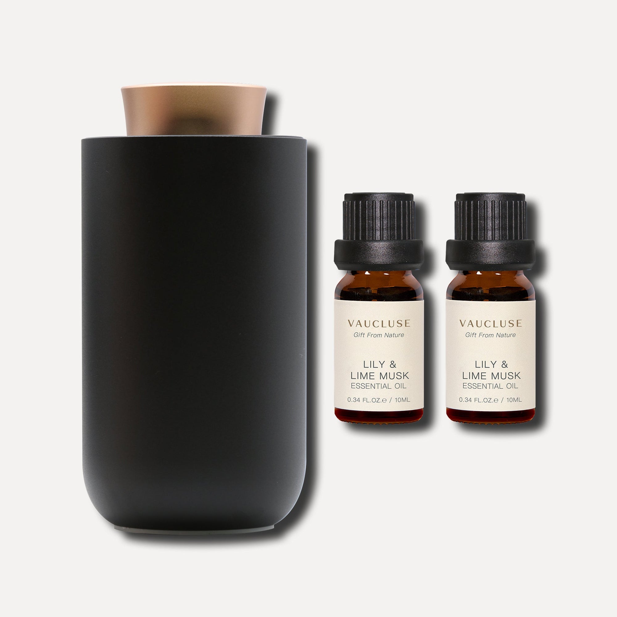 Two 10ml Vaucluse Lily and Lime Musk essential oil amber bottles beside a sleek black aroma diffuser.