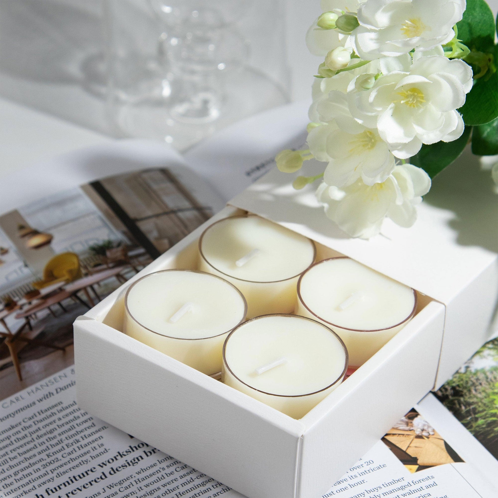 Close up lifestyle shot of a white gift box containing four Vaucluse Jasmine scented tealights, styled on a surface with fresh white jasmine blossoms.